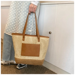 Close-up of the woven hollow texture and brown leather trim on a stylish beach tote bag
