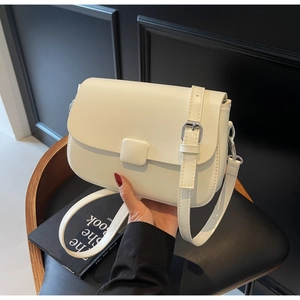 Detail of a creamy white crossbody bag with square buckle and adjustable shoulder strap