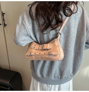 Détail du sac bandoulière beige avec clous argentés et boucles métalliques chic