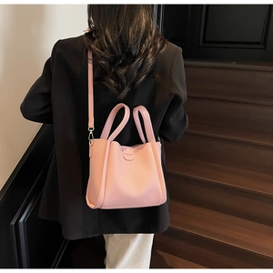 Vue détaillée du sac seau en cuir rose porté en bandoulière sur des escaliers