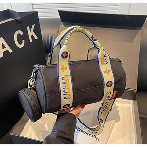 Détail du sac cylindre en nylon noir avec bandoulière jacquard et petit porte-monnaie