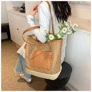 Detail of a large woven straw tote bag with brown leather pocket and dual-color texture