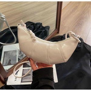 Detail view of cream crescent leather bag featuring elegant pleated stitching and texture