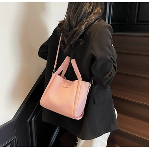 Sac seau rose en cuir grainé porté à l'épaule par un mannequin pour l'aperçu réel