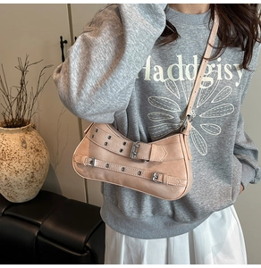 Détail d'un sac baguette en similicuir beige avec boucles argentées et rivets