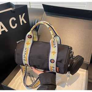 Détail du sac bandoulière cylindrique noir en toile avec larges sangles imprimées colorées