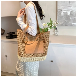 Close-up of handmade straw tote bag with brown leather handles and side pocket detail