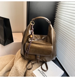 Détail du sac hobo vert olive foncé avec texture cuir glacé et pendentif tressé