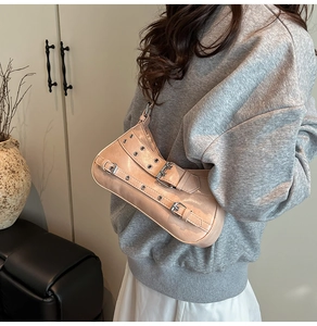 Détail du sac baguette rose vintage avec sangles à boucles et rivets métalliques