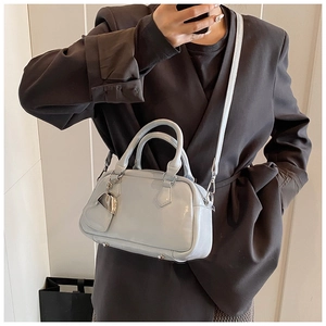 Mirror selfie showing a light blue glossy leather bowling bag with silver heart charm