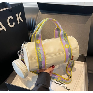 Détail du sac à main cylindrique blanc cassé avec bandoulière tissée et porte-monnaie