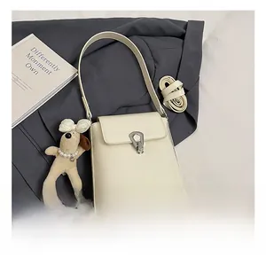 Détail du sac seau blanc cassé avec fermoir argenté et breloque petit chien en peluche