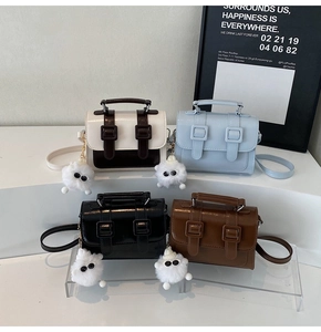 Detailed close-up of four colored mini crossbody bags with cute white plush charms