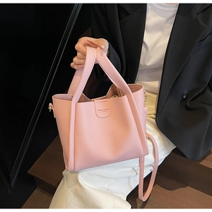 Détail du sac seau rose avec texture grainée et logo de mode embossé sur le cuir