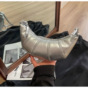 Detailed view of silver metallic croissant bag with pleated stitching and knotted strap
