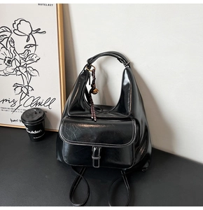 Détail du sac à dos hobo en cuir verni noir avec finition brillante et pompon chic