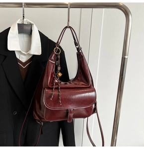 Détail du sac hobo en cuir bordeaux brillant avec poche à boucle et cordelette