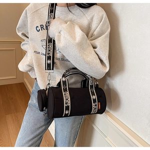 Détail du sac bandoulière cylindrique noir avec sangle tissée et mini porte-monnaie