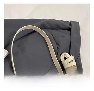 Détail de la poignée du sac seau beige et de la bandoulière réglable sur tissu