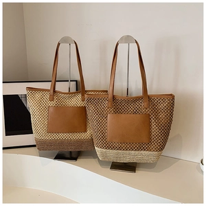 Detail of woven straw tote bags with leather handles and contrasting color blocks