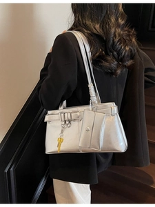 Metallic silver tote bag with trapezoid design, long shoulder strap, and yellow key pendant