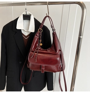 Vue détaillée d'un sac à bandoulière en cuir brillant bordeaux avec poche avant à rabat