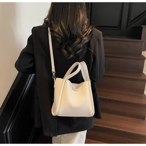 Détail du sac seau minimaliste en cuir crème avec texture litchi et bandoulière