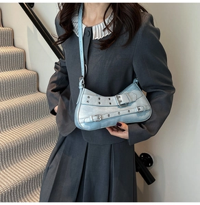 Modèle portant un sac baguette bleu clair demi-lune avec détails de sangles à œillets