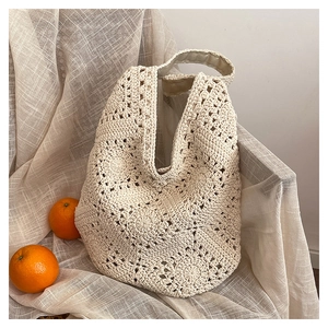 Detail of handmade cream crochet tote bag with hollow flower patterns and cotton texture