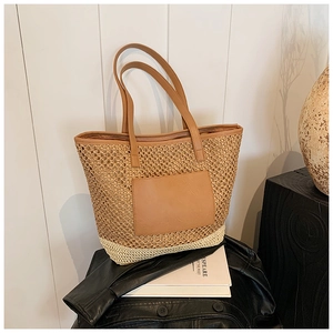 Detail of woven straw tote bag featuring contrast mesh texture and brown leather straps