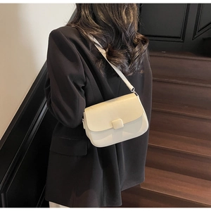 Detail view of cream crossbody bag styled with a black suit in a vintage setting