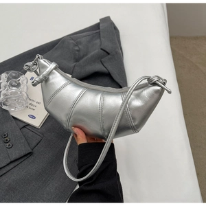 Close-up of metallic silver croissant bag with distinct stitching and knotted strap details