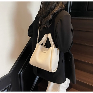 Détail du sac seau en cuir grainé blanc cassé porté par un mannequin pour le quotidien