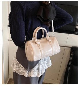 Detail view of cream white Boston bag with glossy finish and silver metal hooks