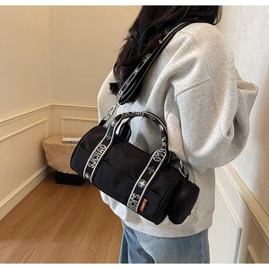 Détail du sac à bandoulière noir cylindrique avec sangle fleurie et petite pochette ronde