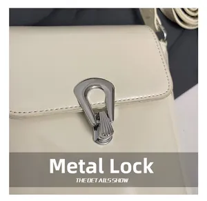 Détail du fermoir en métal argenté et des coutures sur un sac seau blanc crème