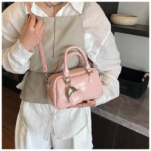 Pink glossy bowling bag with heart charm shown on model in a casual home setting