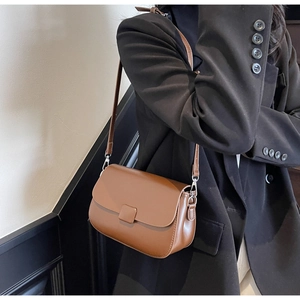Brown vintage faux leather crossbody bag worn over a black blazer for office style