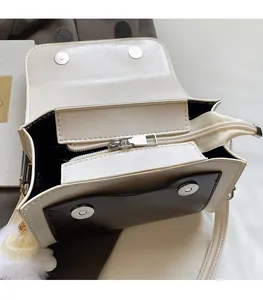 Detail view of contrast-color satchel showing inner compartment and silver hardware