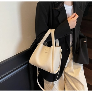 Détail du sac seau blanc cassé avec cuir à grain lychee et logo sur le devant