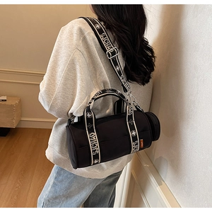 Détail d'un sac bandoulière cylindrique noir en nylon avec sangle large et mini pochette