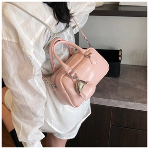 Detail of pink leather bowling bag showing silver heart charm and crossbody strap