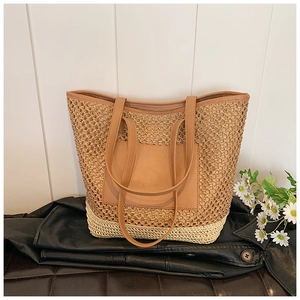 Detail showing two-tone woven texture and brown leather pocket on straw tote bag