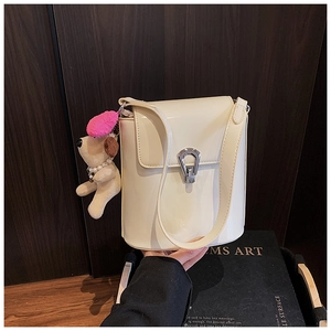Détail d'un sac seau beige avec boucle argentée et charmant pendentif chien en peluche