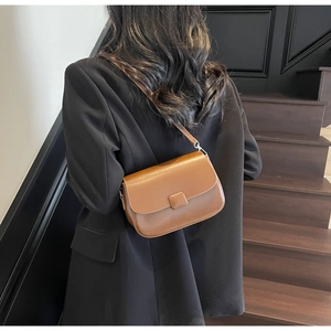 Rear view of a model wearing the brown vintage faux leather crossbody bag in a hallway