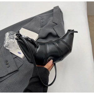 Close-up of black glossy PU leather croissant bag with fine stitching and shoulder strap