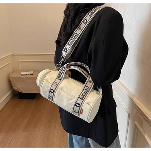 Détail du sac cylindrique en toile crème avec large bandoulière tissée vintage