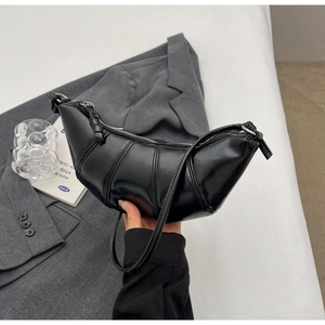 Detail of a black crescent horn bag with sleek leather finish and vertical stitching