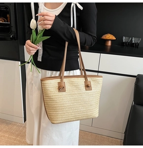 Détail du sac cabas en paille tissée avec bordure en cuir brun et lanière nouée