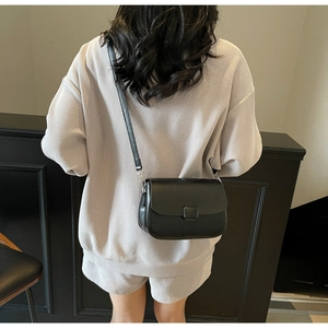 Detailed back view of a minimalist black matte leather crossbody bag worn by a model
